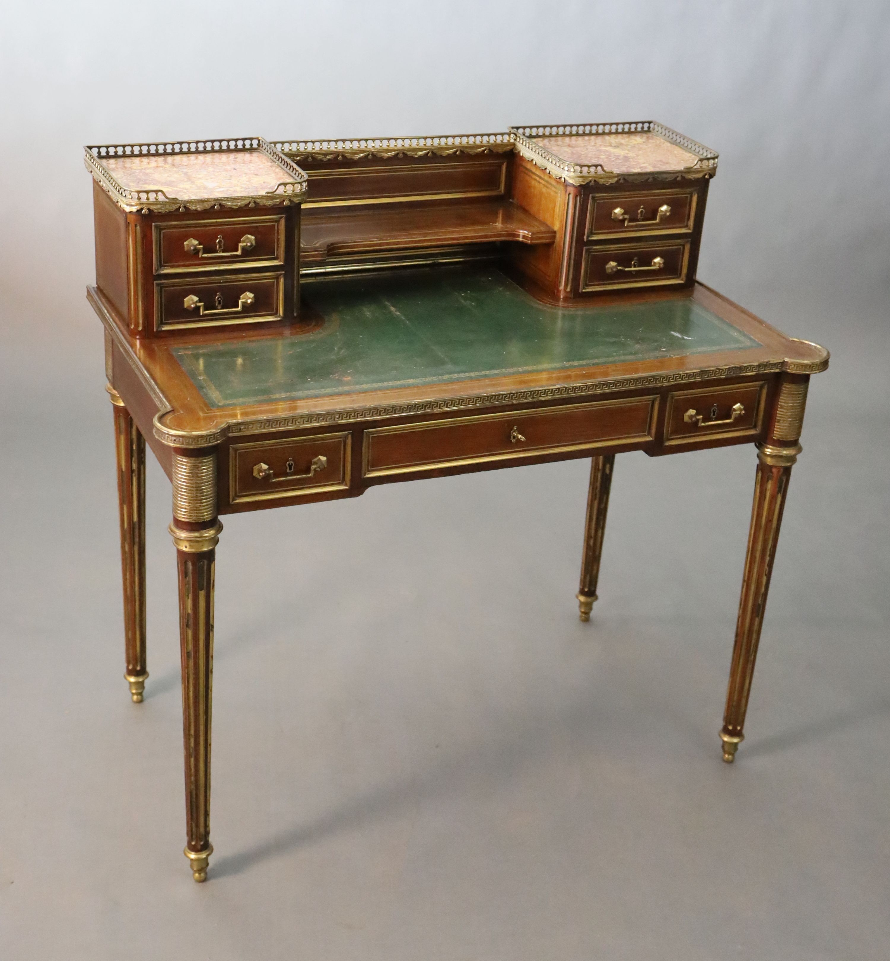 A French Louis XVI style brass mounted marble inset mahogany writing table, W.101.5cm D.7.5cm H.93.5cm